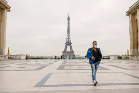 An illustrative photo of a man in a mask standing in front of the Eiffel Tower