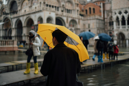 An illustrative photo of a man in black coat holding yellow umbrella.