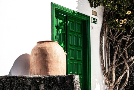 An illustrative photo of a green wooden door beside brown clay vase