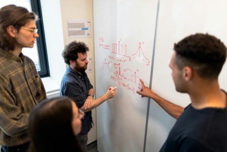 A small group of people analyzing notes on a whiteboard