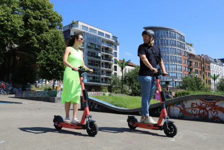 An illustrative photo of two people riding scooters in a city