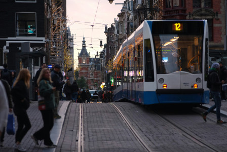 An illustrative photo of a white and blue tram on a busy city street