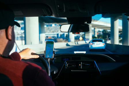 An illustrative photo of a man driving in a car while looking on the navigator
