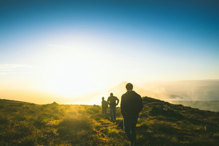 An illustrative photo of three people hiking on a mountain during sunset