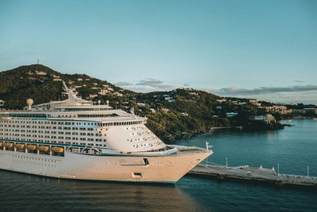 An illustrative photo of a white cruise ship on sea near a coast.