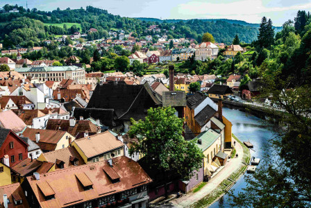 An illustrative photo of a river running through a small town next to a lush green hillside.