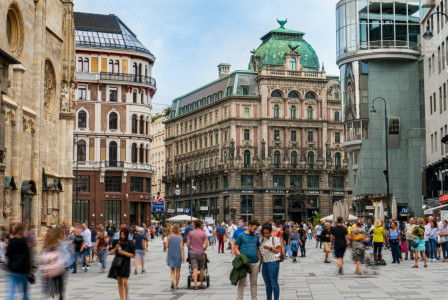 An illustrative photo of people walking on a central street near beautiful buildings
