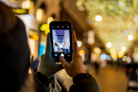 An illustrative photo of a person taking a picture of Christmas lights