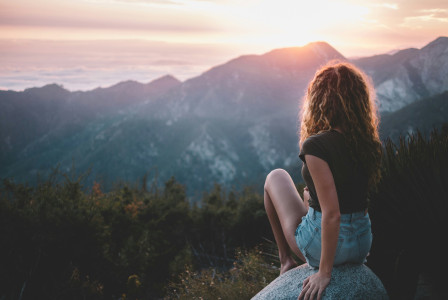 An illustrative photo of a woman sitting on rock.