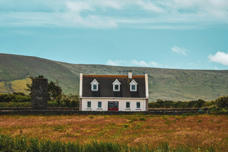 An illustrative photo of a white house on top of green field.