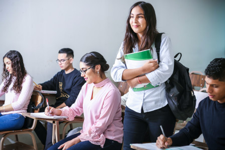 An illustrative photo of a student carrying a textbook in the class