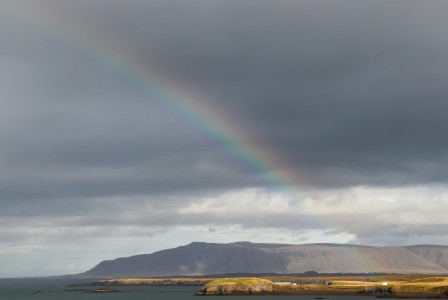 An illustrative photo of a rainbow in the sky over a body of water.