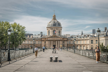 An illustrative photo of people walking on sidewalk near buildings.