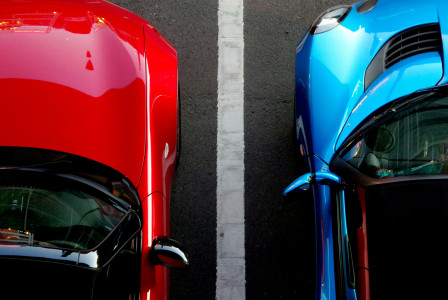 Image by Unsplash An illustrative photo of blue and red cars on a parking lot.