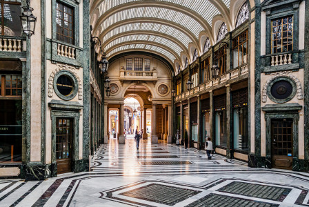 An illustrative photo of people walking through a beautiful hallway building.