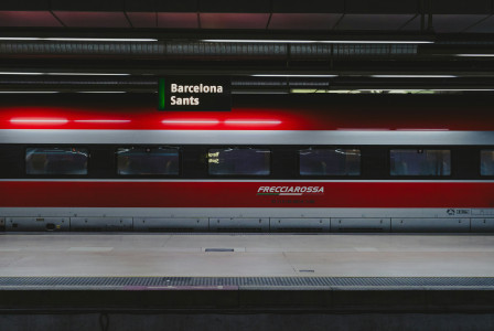 An illustrative photo of a red and silver train parked at a train station.