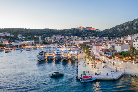 An illustrative photo of boats near a coast with buildings during evening.