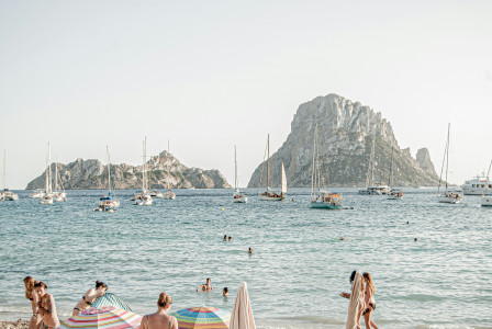 Image by Unsplash An illustrative photo of people on the beach with boats in the sea in the background.