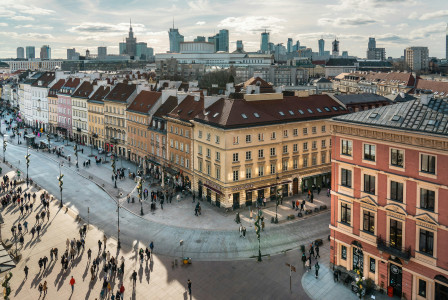 An illustrative photo of people walking down a street next to tall buildings.