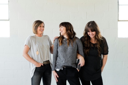 An illustrative photo of three women standing together and smiling.