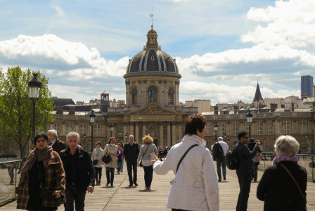 An illustrative photo of people walking on sidewalk near brown concrete building.