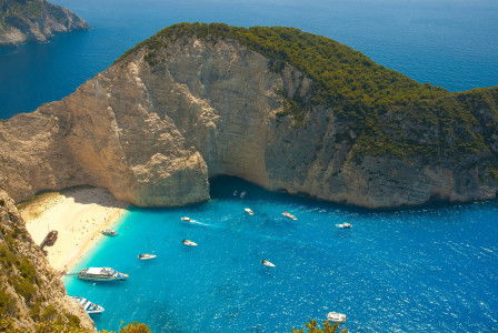 An illustrative photo of boats in a body of water near a green island.