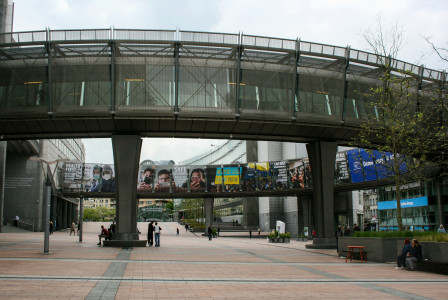 An illustrative photo of a pedestrian bridge over a street with people walking on it.