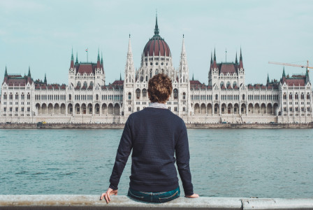 An illustrative photo of a man sitting in front of the Hungarian Parliament building.