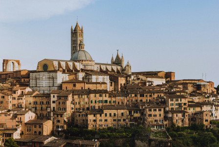 An illustrative photo of white and brown concrete houses on a hill.