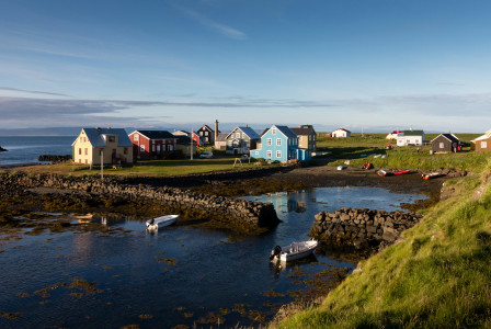 An illustrative photo of houses near a body of water under blue sky.