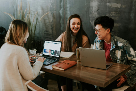 An illustrative photo of three people sitting in front of table working together.