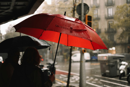 An illustrative photo of a person holding a red umbrella in the rain.