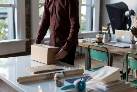 An illustrative photo of a person holding cardboard box.