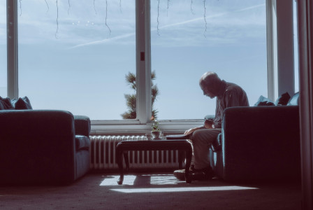 An illustrative photo of a man sitting on a couch.
