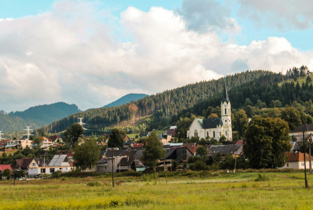 An illustrative photo of houses near green trees and mountains.