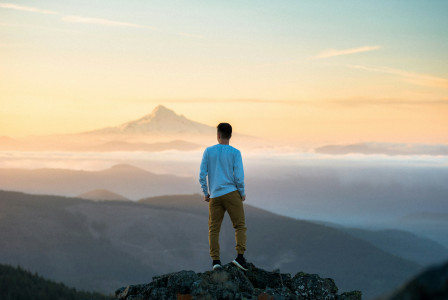 An illustrative photo of a man standing on top of a mountain.