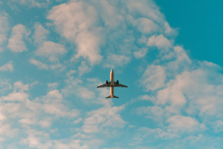 An illustrative photo of a white airplane flying in the sky.