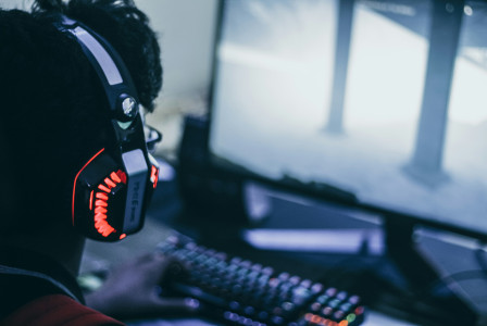 An illustrative photo of a person with headphones playing video game.