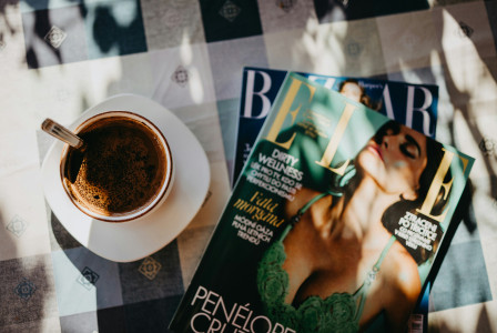 An illustrative photo of a cup of coffee and a magazine on a table.