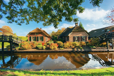 Image by Unsplash An illustrative photo of two brick houses near a river.