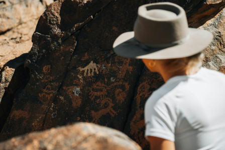 An illustrative photo of a person standing next to a rock.