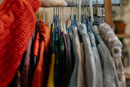 Hand browsing clothes on a clothing rack.