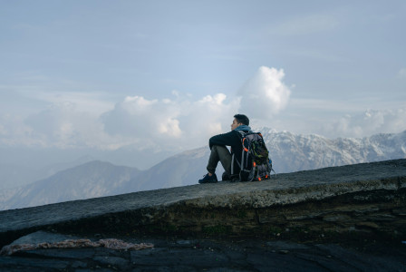 An illustrative photo of a man sitting on top of a mountain.