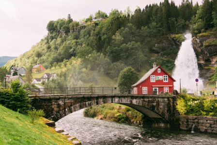 An illustrative photo of a red house sitting on top of a lush green hillside.