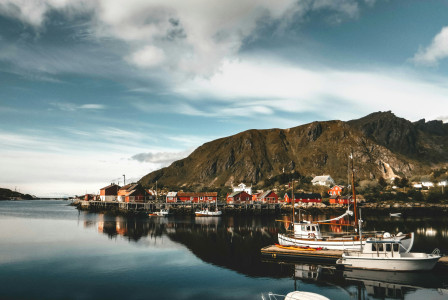 An illustrative photo of a house near a dock and a mountain.