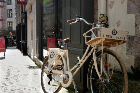 An illustrative photo of a brown city bike parked beside a building.
