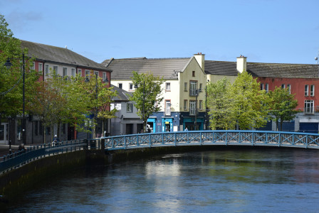 An illustrative photo of a bridge over a river in a small city.