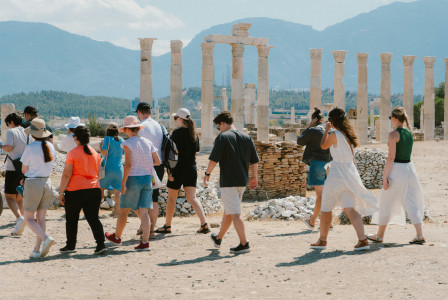 An illustrative photo of a group of people walking near a monument in Greece.