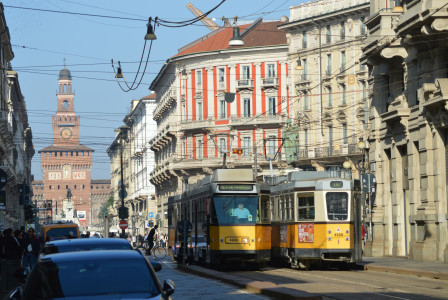 An illustrative photo of a yellow and black tram on a city street.