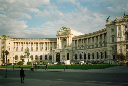 An illustrative photo of people walking near white concrete building during daytime.